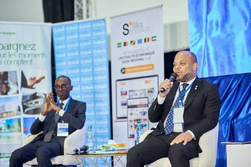 Intervenant au micro devant les kakémonos des partenaires du salon